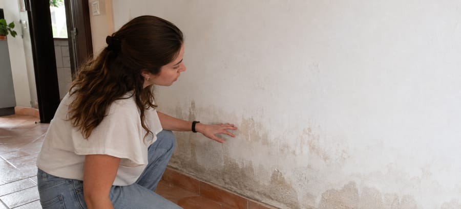 Persona revisando manchas de humedad en una pared de su vivienda recién comprada